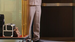 A man in a beige suit standing next to a golden elevator door. - Ciriaco Hotel and Resort (Calbayog)