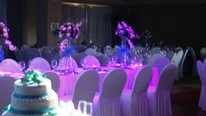 A banquet hall with round tables set for a formal event, featuring white tablecloths and chairs with white covers. - Ciriaco Hotel and Resort (Calbayog)