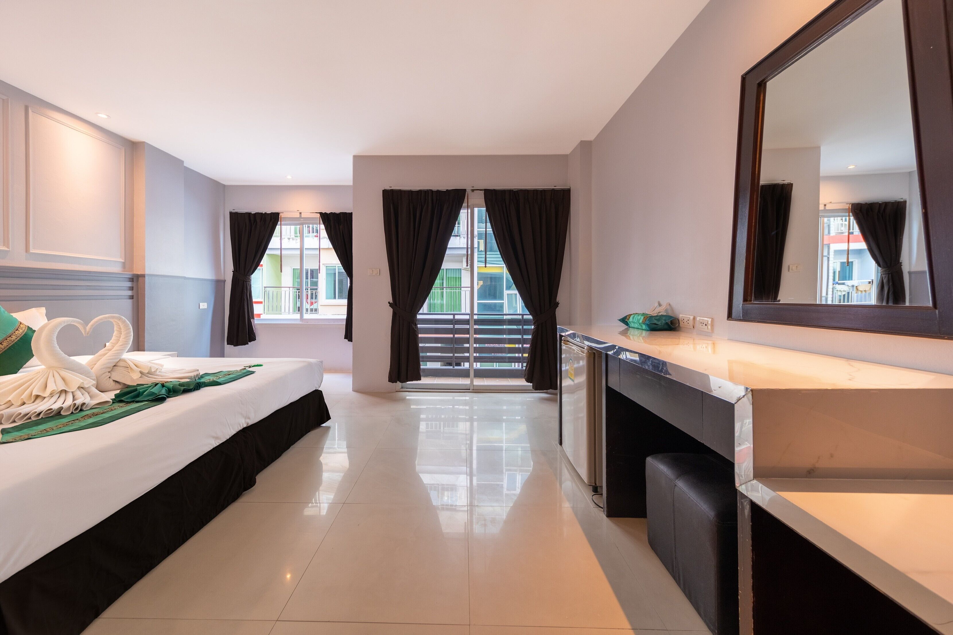 Ein Hotelzimmer mit Bett, Schreibtisch, Spiegel und Blick ins Freie.