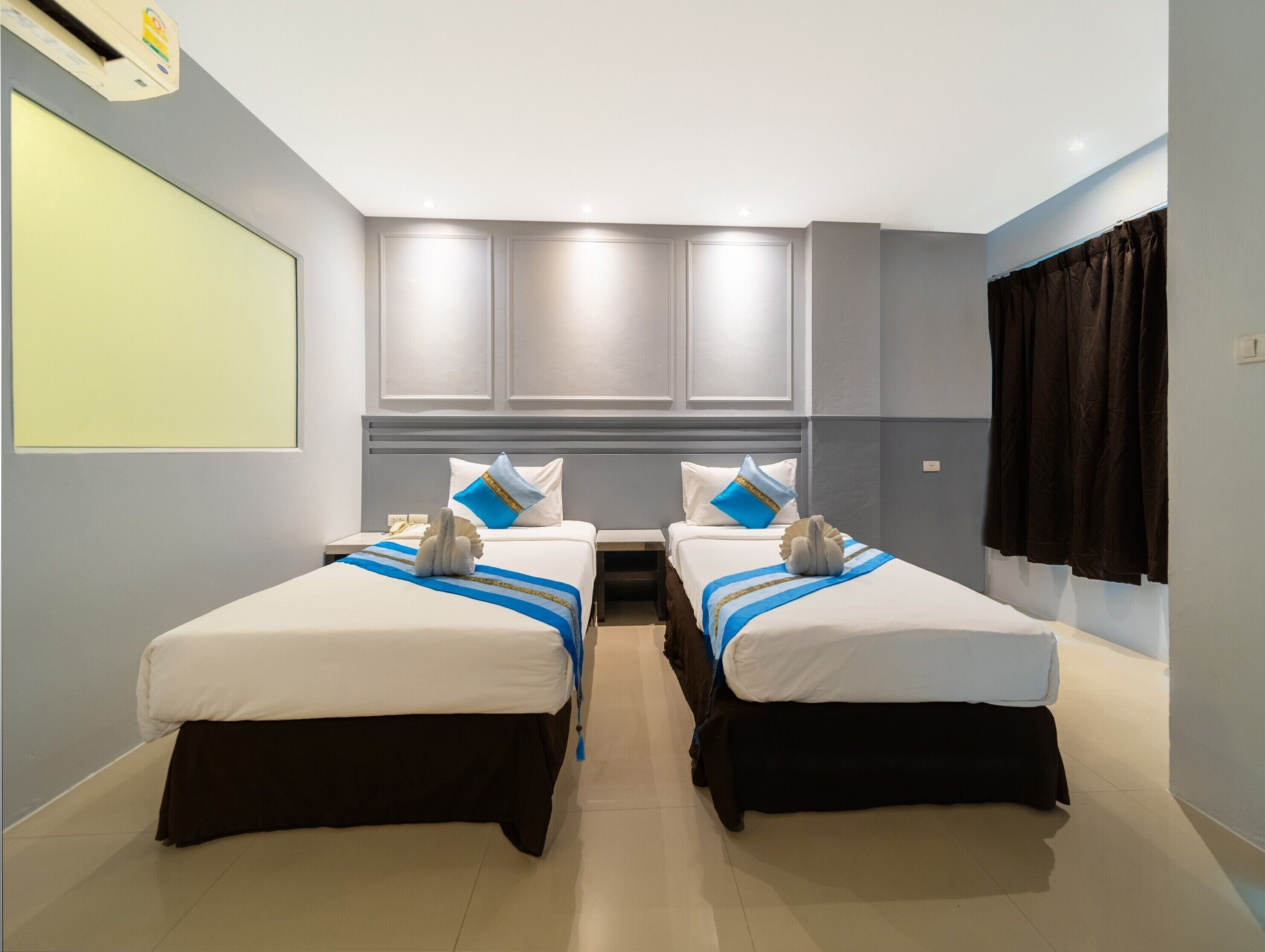 Ett hotellrum med två separata sängar, ett stort fönster och en platt-TV.