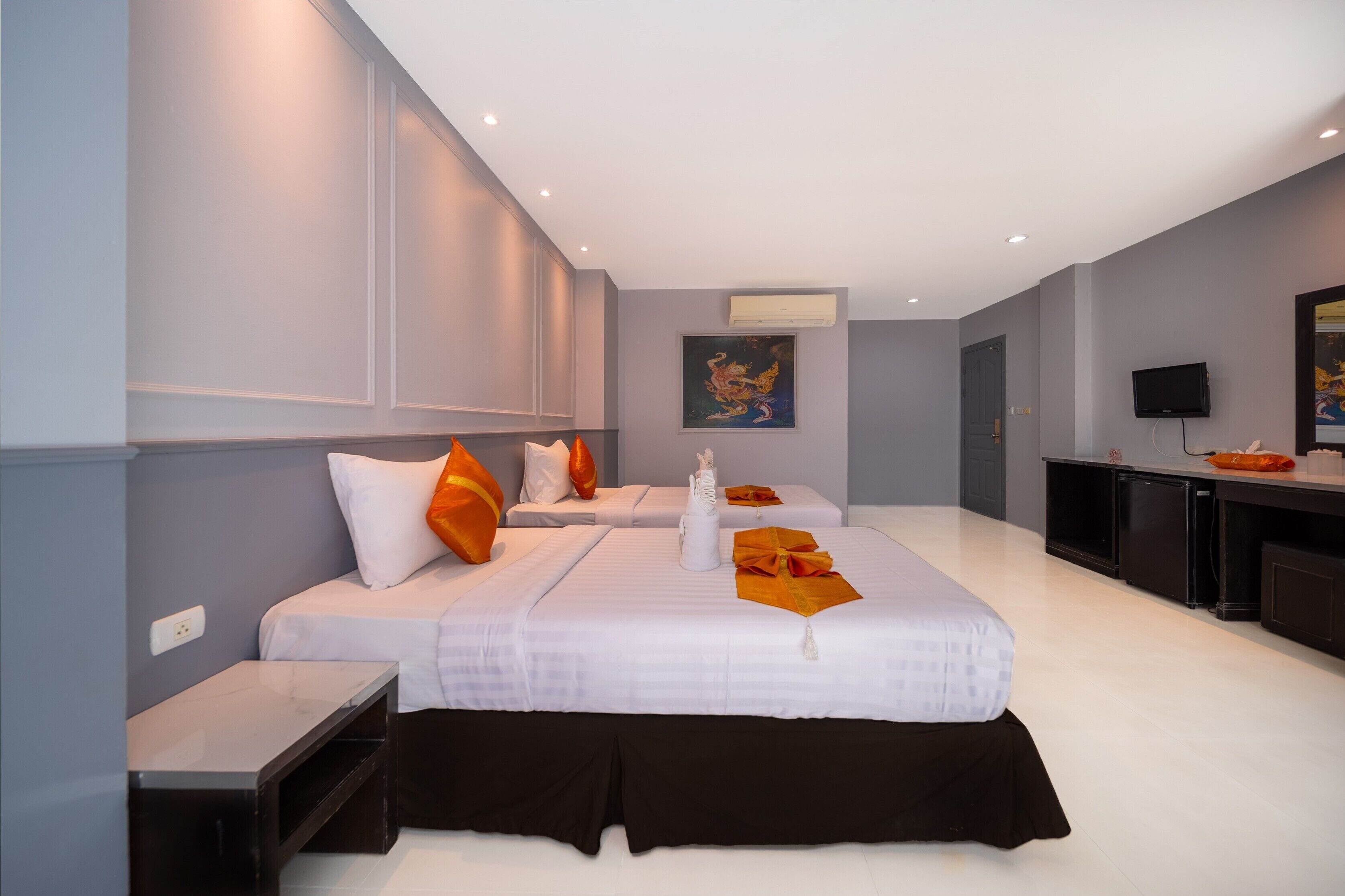 A modern hotel room with two beds, a flat-screen TV, a minibar, and a painting on the wall.