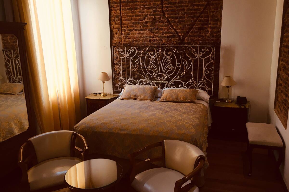 Une chambre d’hôtel avec un grand lit, deux tables de chevet, une chaise et une petite table.