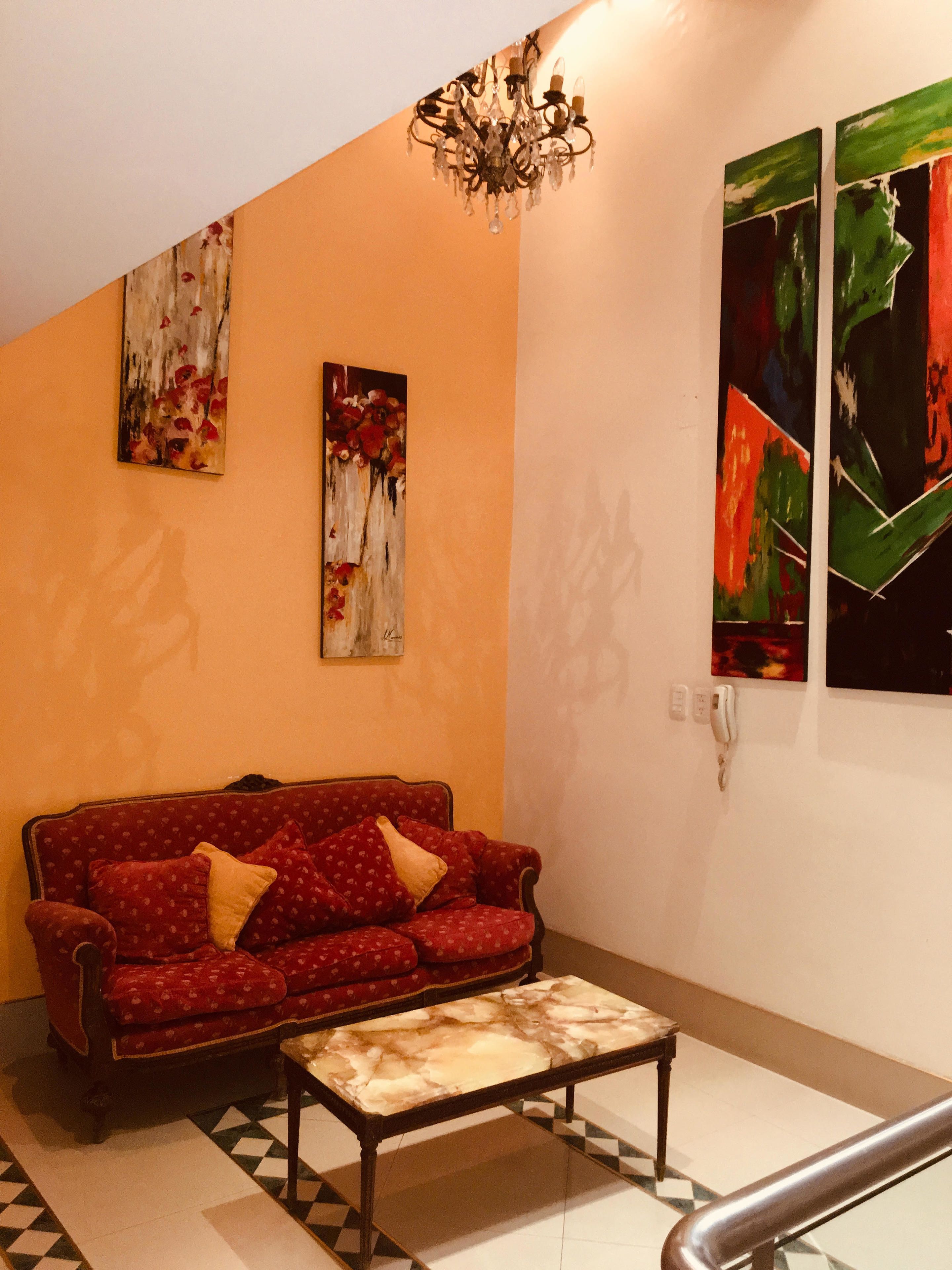 A living room with a red sofa, a coffee table, and artwork on the walls.