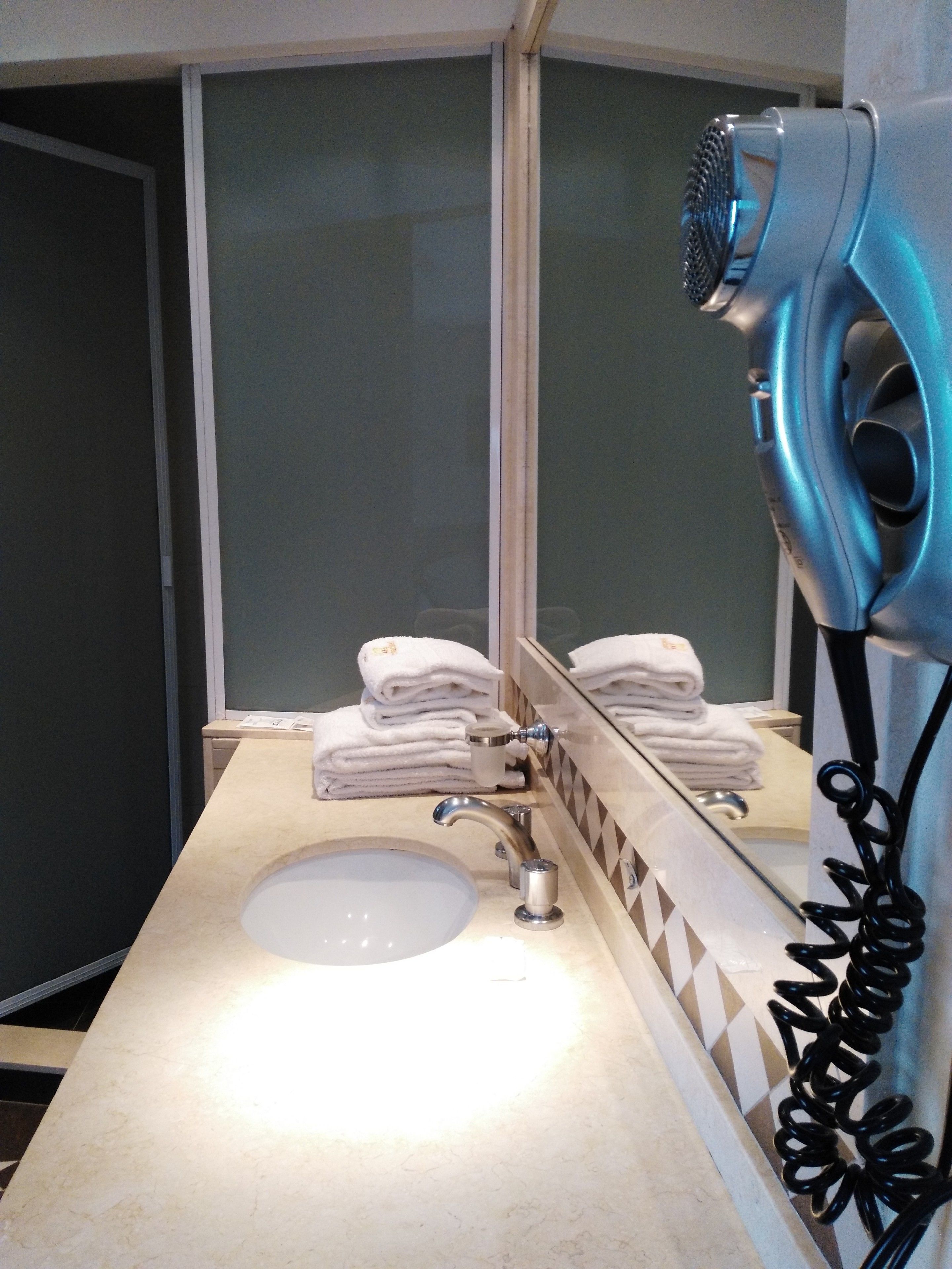 A bathroom with a sink, a mirror, and a hairdryer.