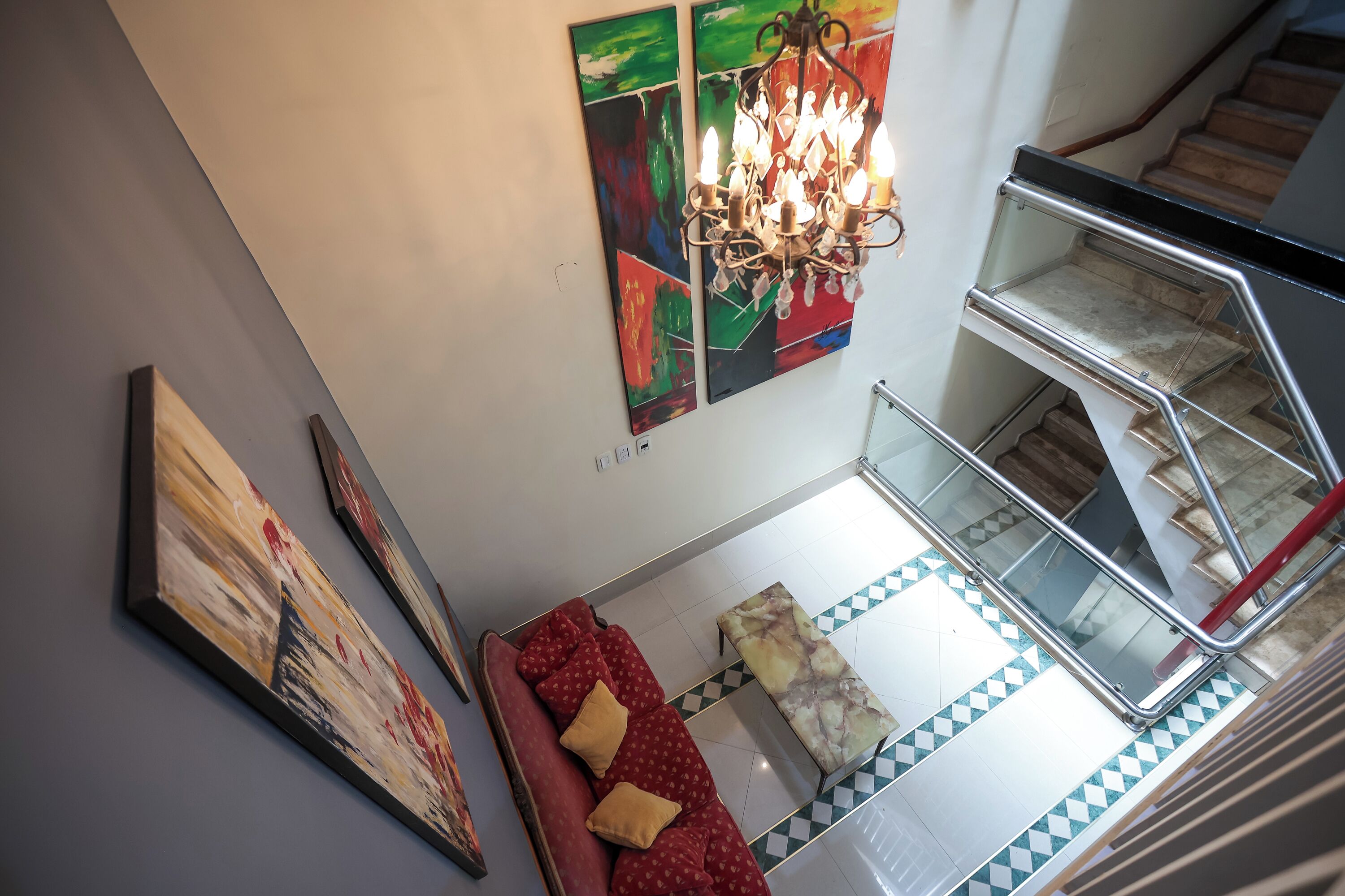 Un intérieur moderne agrémenté d’un escalier, d’un lustre et d’œuvres d’art abstraites accrochées aux murs.