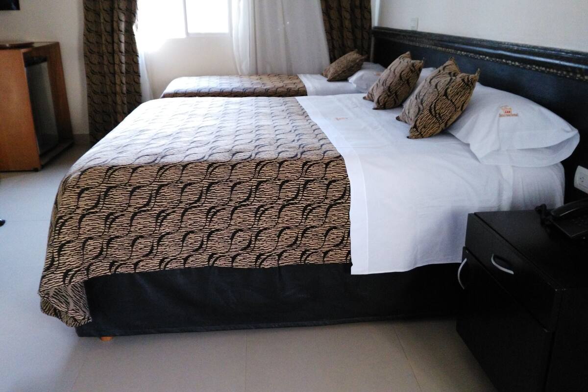 Une chambre d’hôtel avec deux lits, un bureau et une chaise.
