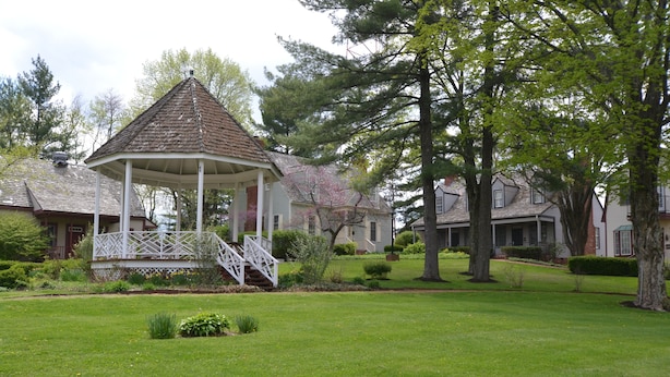 A gazebo with a white railing and a staircase leading up to it, surrounded by a well-maintained lawn and trees. - Century Suites Hotel (Bloomington)