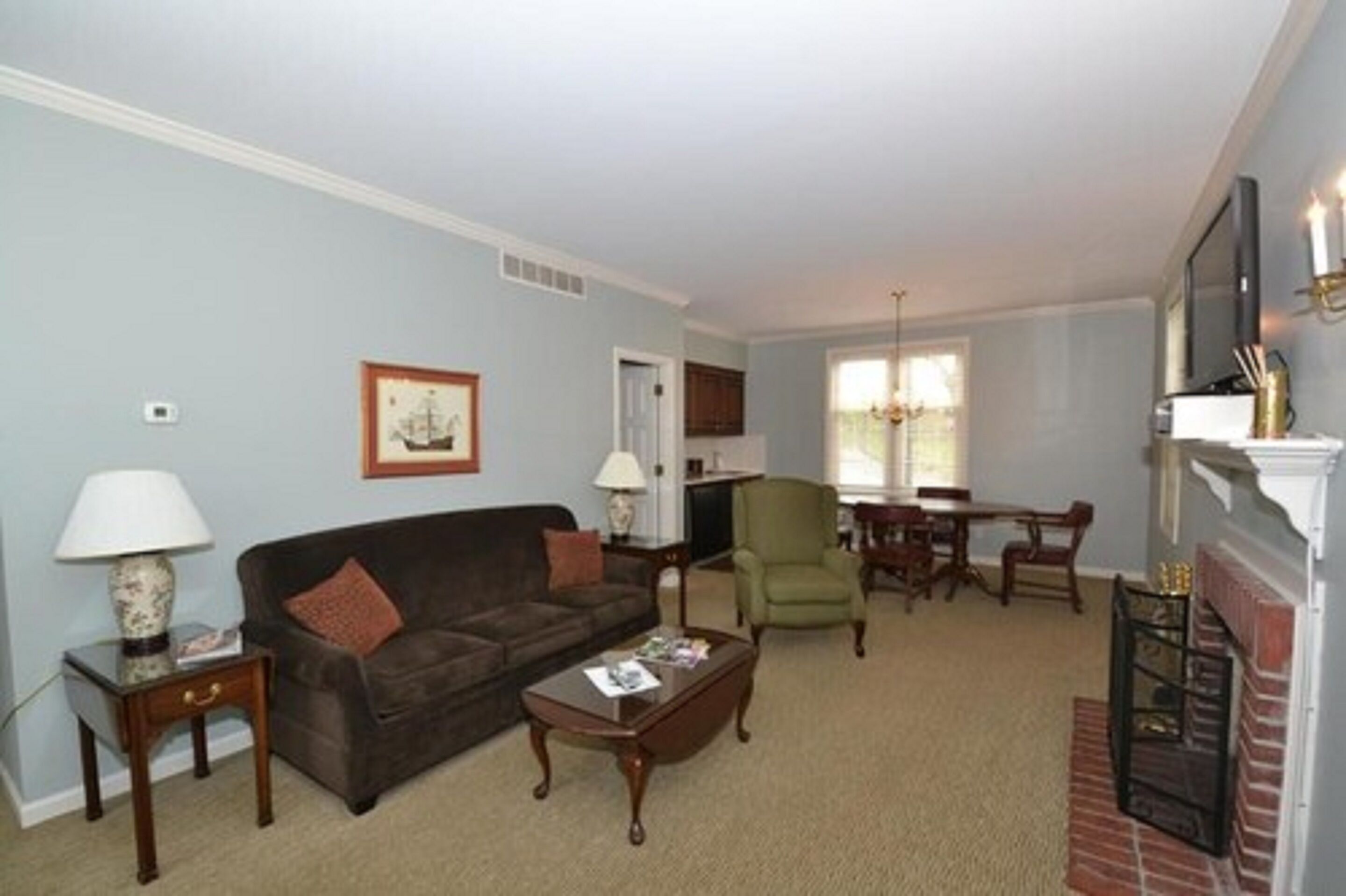 A living room with a sofa, armchair, coffee table, and fireplace.