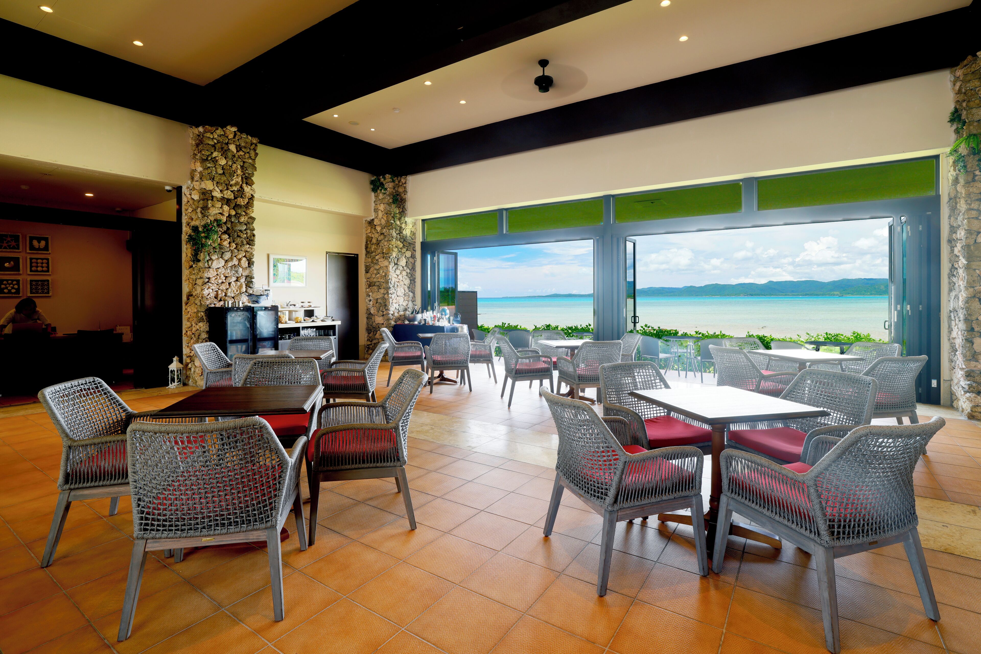 A restaurant with outdoor seating, stone walls, and a view of the ocean.