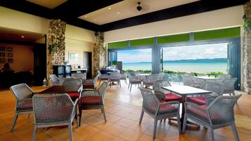 A restaurant with outdoor seating, stone walls, and a view of the ocean.