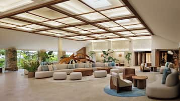 Een ruime lobby met een hoge plafond, een groot zitgedeelte en een trap naar de verdiepingen.