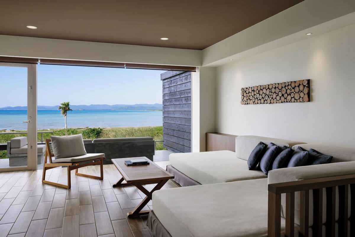 A modern room with a balcony, a sofa, a bed, and a table.