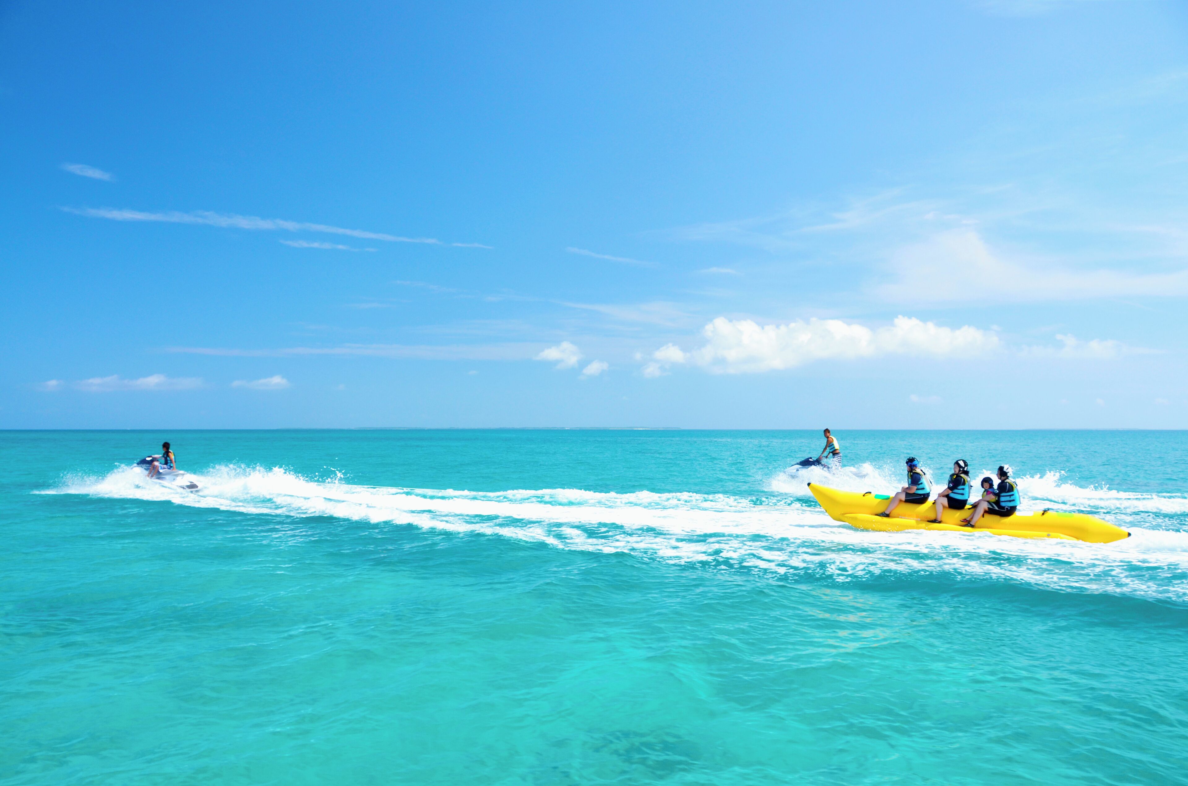 Un groupe de personnes se trouve dans un canot jaune sur une mer turquoise, sous un ciel dégagé.