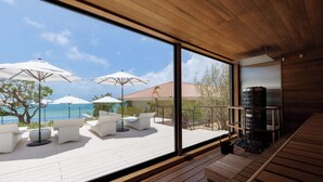 A modern outdoor deck with white furniture and umbrellas, overlooking a pool and ocean.