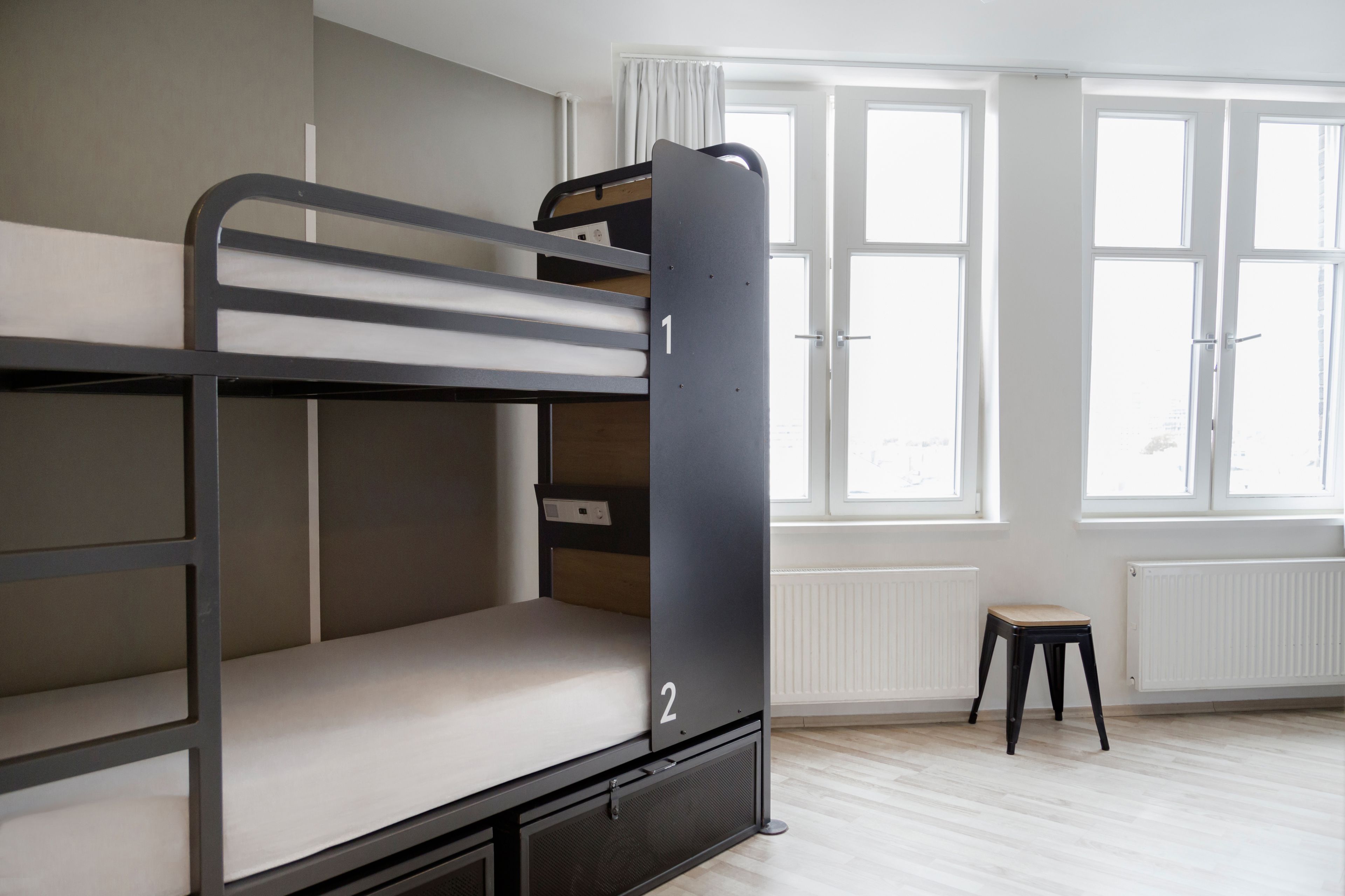 Ein Schlafzimmer mit Etagenbetten, einem Fenster und einer Heizung.