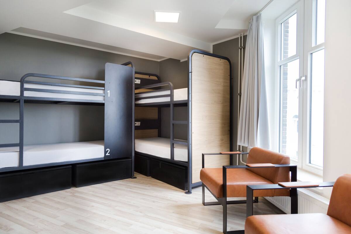 A dormitory room with bunk beds, a desk, and a chair.