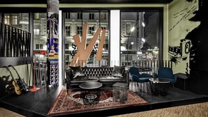 A modern lounge area with a leather sofa, two blue chairs, a coffee table, and a patterned rug. - Generator Hamburg (Hamburg)