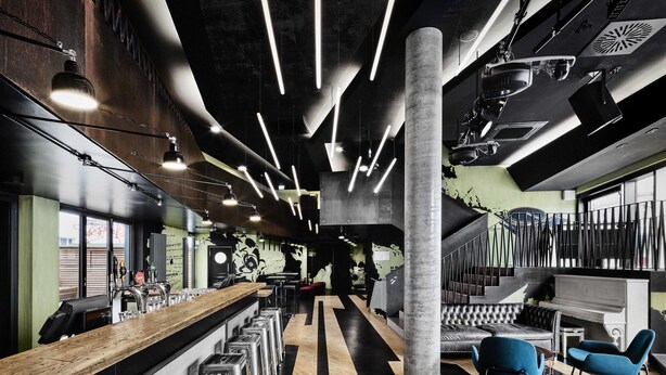 A modern bar area with a long counter, stools, and a piano. - Generator Hamburg (Hamburg)