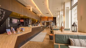 A modern hotel lobby with a reception desk, seating area, and large windows. - Generator Hamburg (Hamburg)