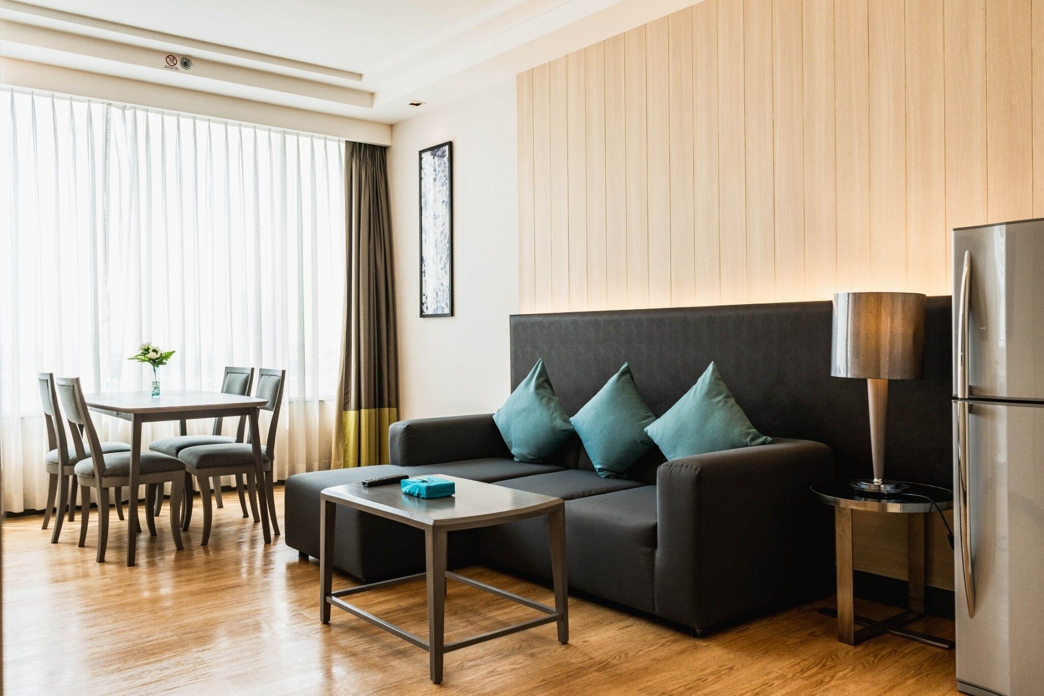 Ein modernes Wohnzimmer mit einer Couch, einem Couchtisch, einem Esstisch mit Stühlen und einem Kühlschrank.