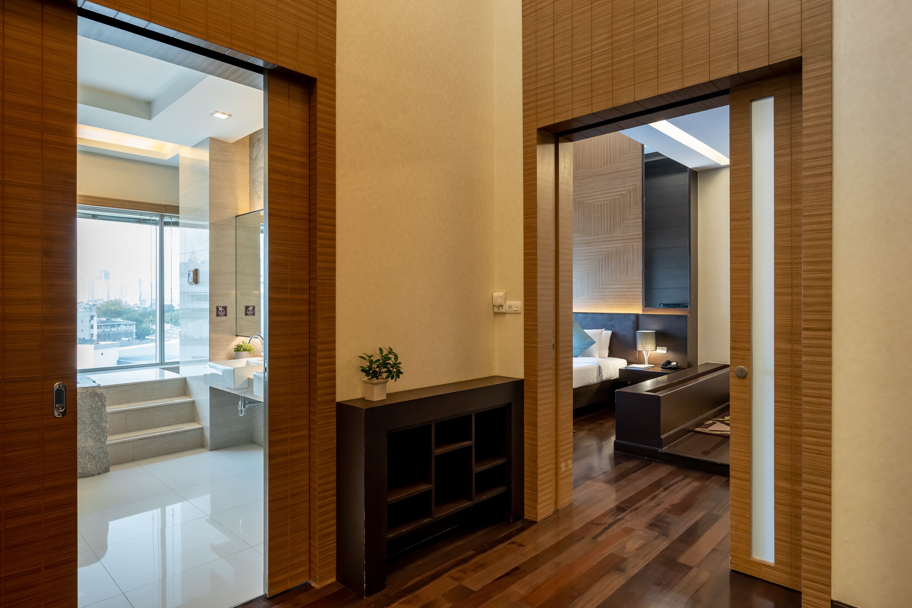 A modern interior with a wooden floor, a fireplace, and a view of the city through large windows.