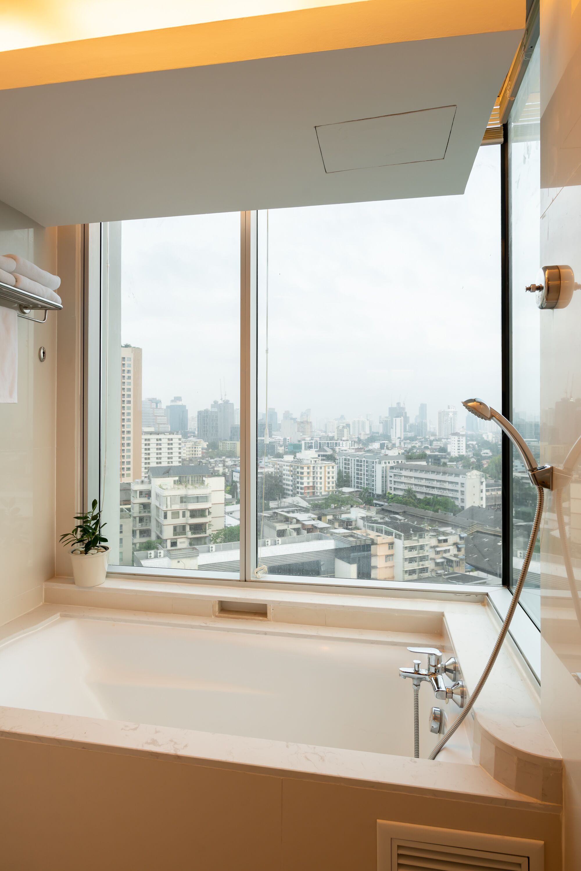 Un baño moderno con una bañera grande, una ventana con vistas a la ciudad y un cabezal de ducha.