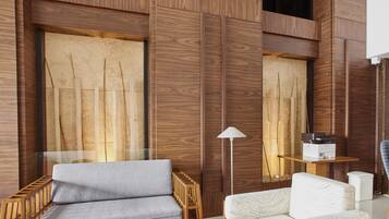 Una habitación moderna con paneles de madera, un sofá gris, un sofá blanco y una lámpara de pie.