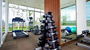 A gym with exercise equipment, a treadmill, and a mirror reflecting the equipment.