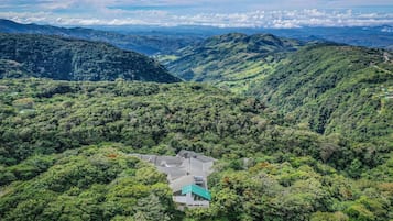Vista aérea de una zona montañosa con un edificio rodeado de denso bosque.
