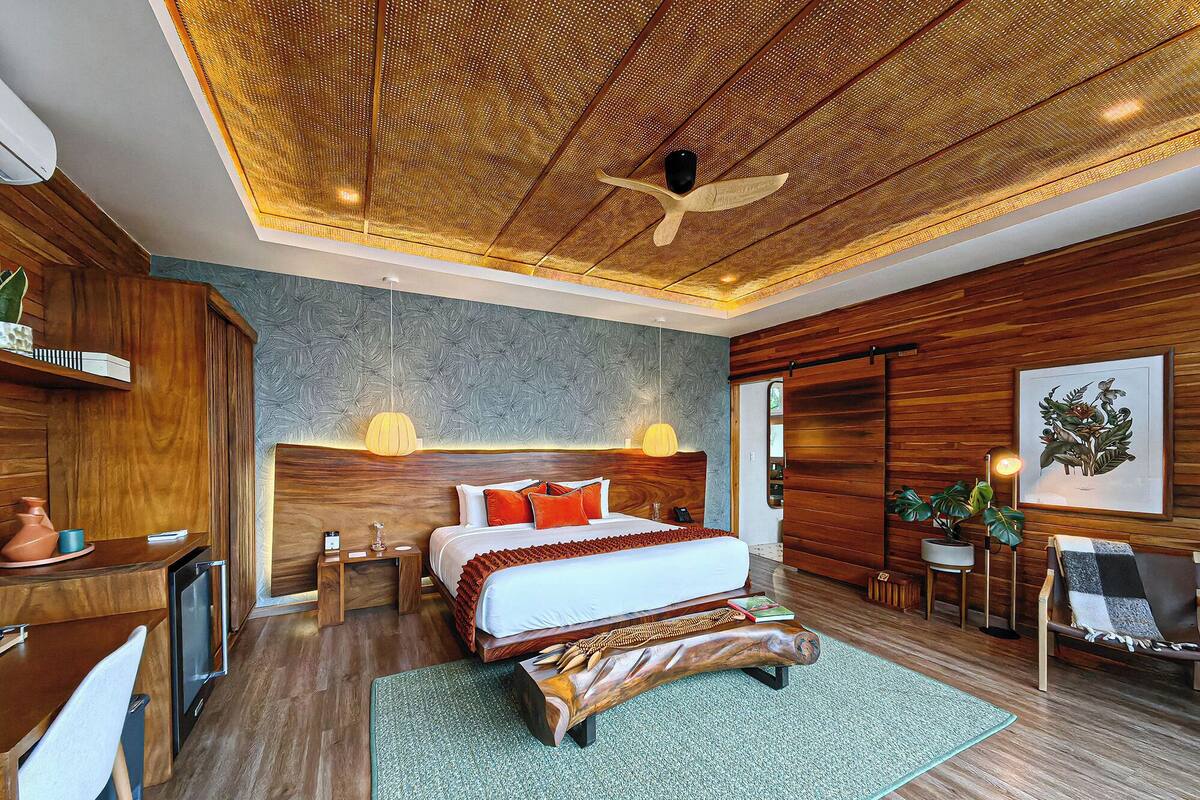 Ein modernes Schlafzimmer mit einem großen Bett, einem Holzkopfende und einem Deckenventilator.