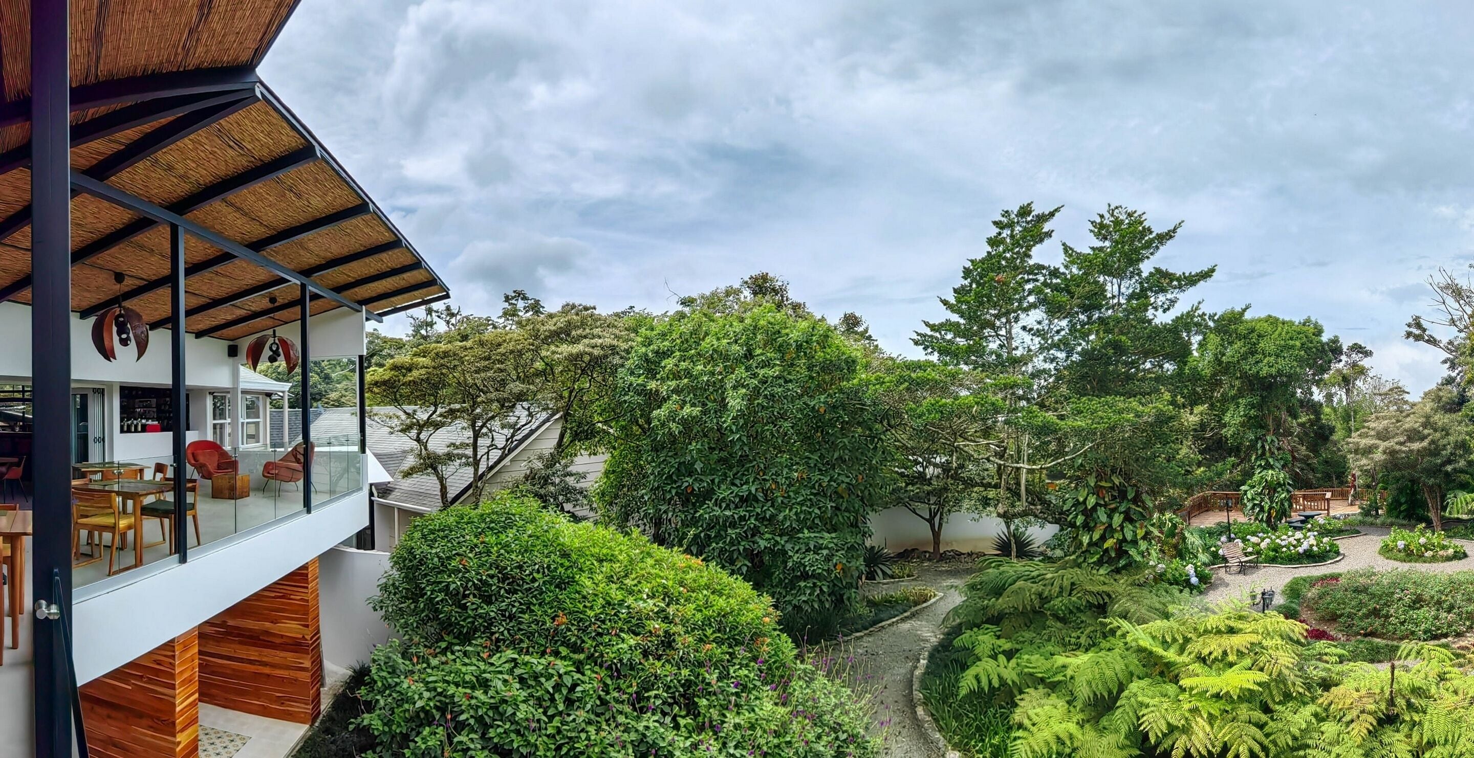 A modern house with a glass balcony overlooking a lush garden.
