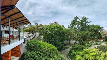 A modern house with a glass balcony overlooking a lush garden.