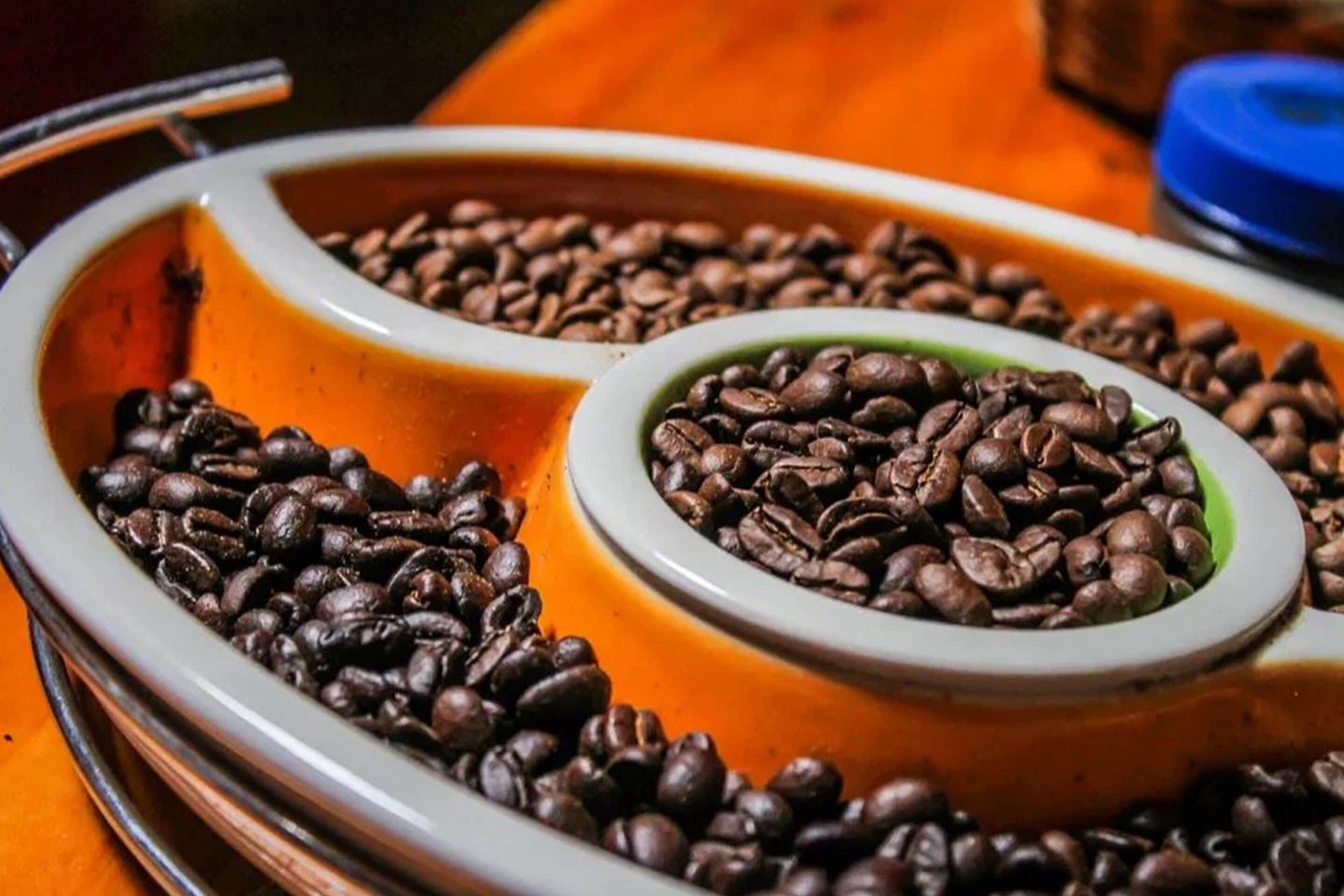 A coffee grinder with two compartments, one filled with coffee beans and the other empty.