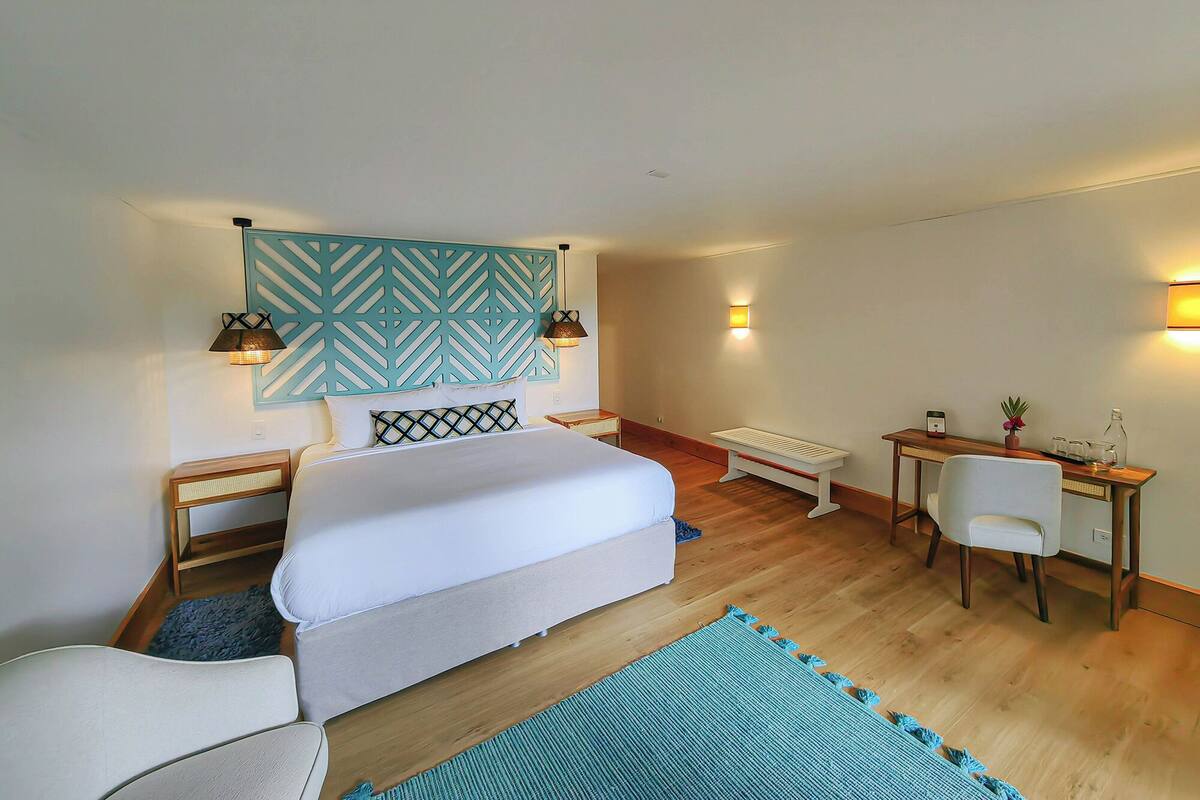 Ein Schlafzimmer mit Bett, Nachttischen, Schreibtisch, Stuhl und einer Wandleuchte.