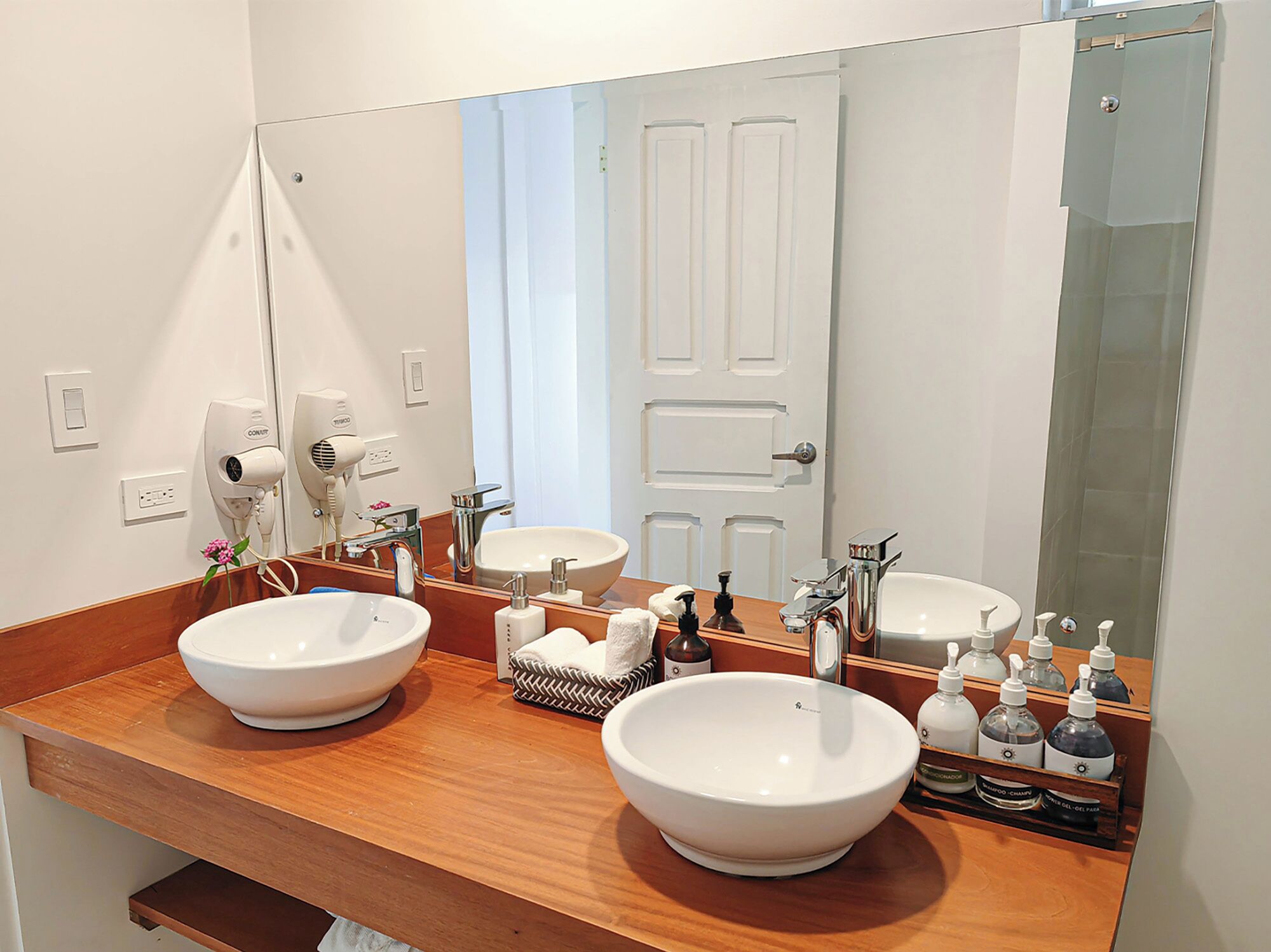 A bathroom with two large white sinks, a mirror, and a wooden countertop.