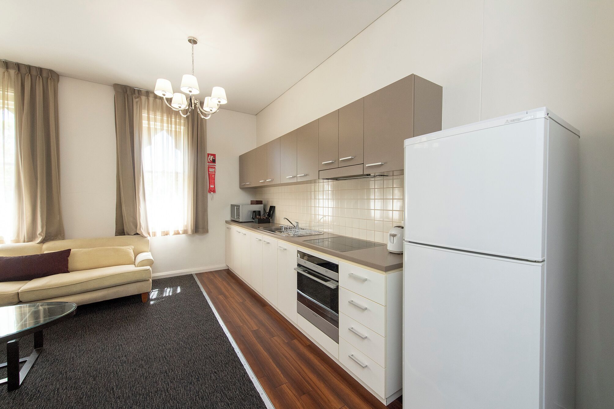 A modern kitchen with white cabinets, a built-in oven, and a refrigerator.