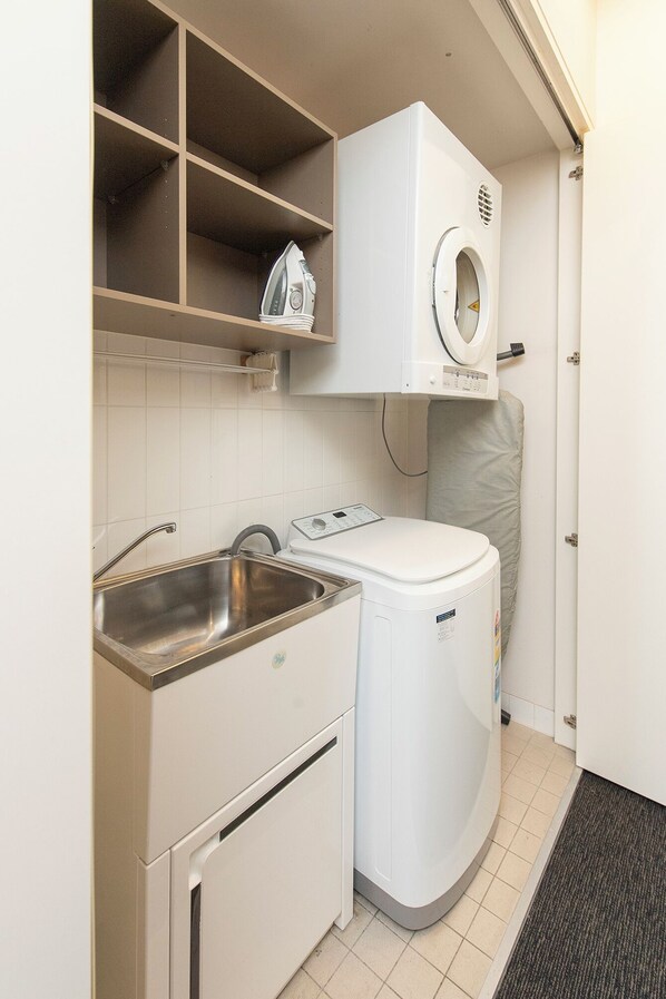 A compact laundry room with a washing machine, a dryer, and a sink. - Adabco Boutique Hotel Adelaide (Adelaide)
