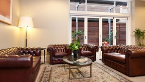 Een woonkamer met twee leren banken, een glazen salontafel en een kamerbreed tapijt met een patroon.