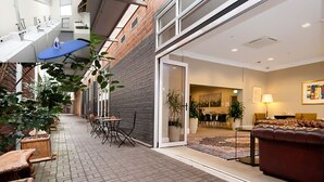 Een hotelgang met een bakstenen muur, een eetgedeelte met tafels en stoelen, en een bank in de woonkamer.