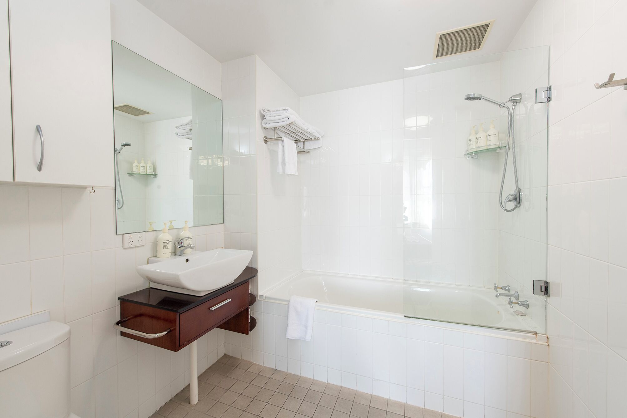 Une salle de bain moderne avec une douche à parois de verre, un lavabo blanc et un grand miroir.