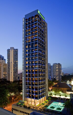 A high-rise hotel with multiple floors, a rooftop pool, and a well-lit facade. - Novotel Living Singapore Orchard (Singapore)