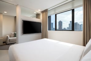 Habitación de hotel con una cama grande, un televisor de pantalla plana, un sofá y vistas a la ciudad.