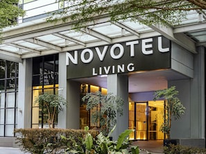 Entrada de hotel con un gran letrero que dice 'NOVOTEL LIVING'.