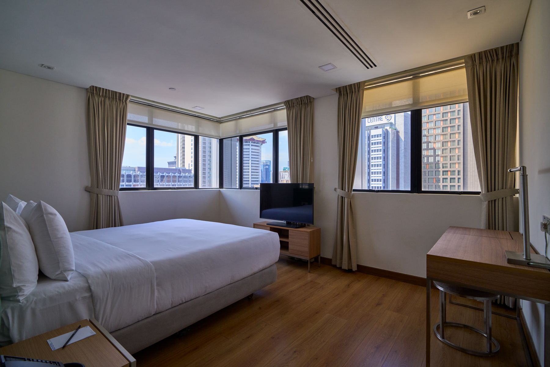 A hotel room with a large bed, a desk, a chair, and a TV.