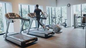 Un gimnasio con cintas de correr, bicicletas estáticas y máquinas de pesas.