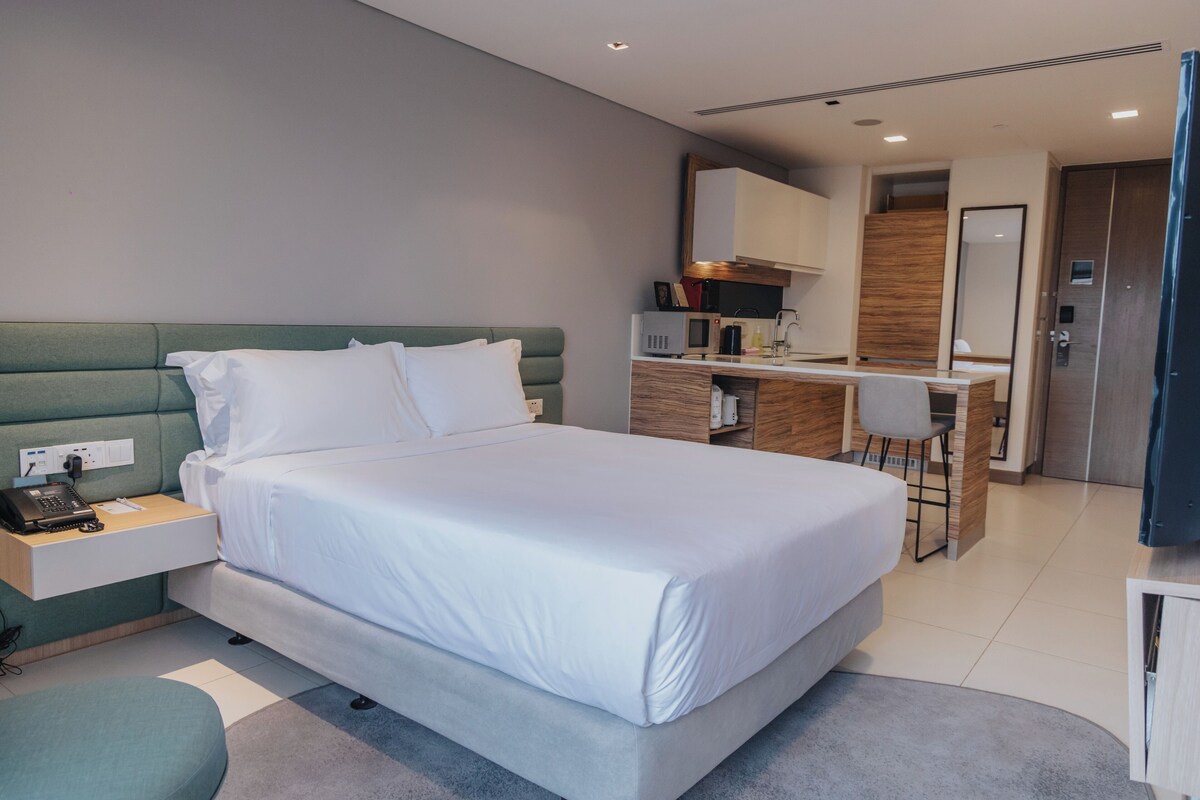 A modern hotel room with a large bed, a desk, and a chair.