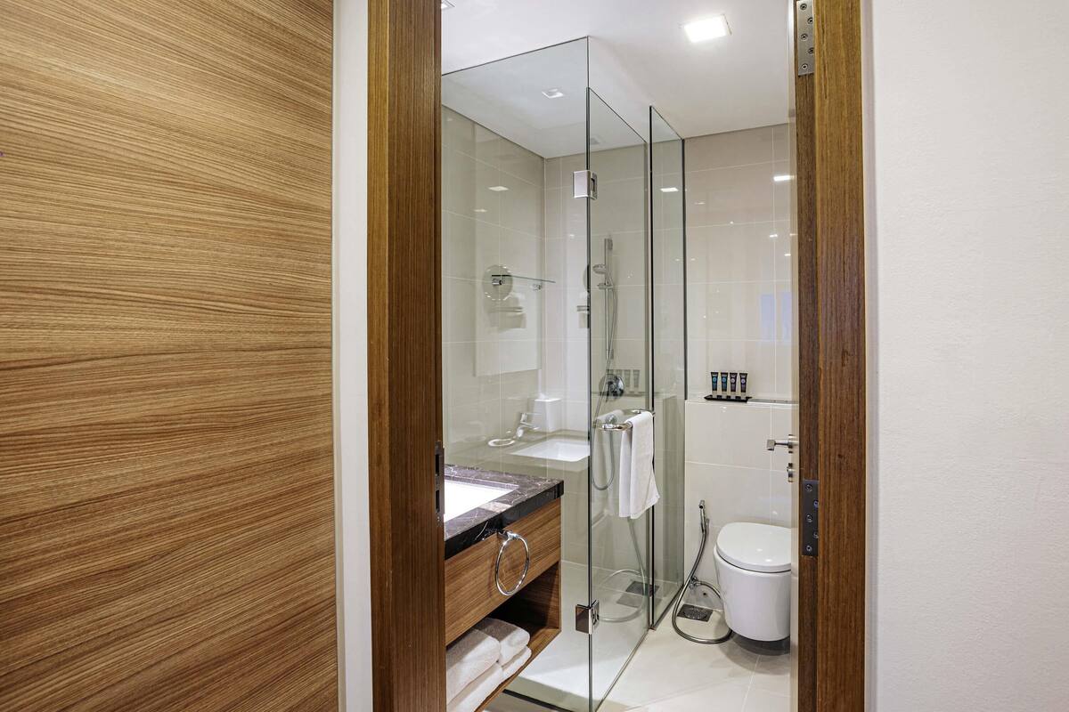 A modern bathroom with a glass shower enclosure, a wooden vanity, and a white toilet.