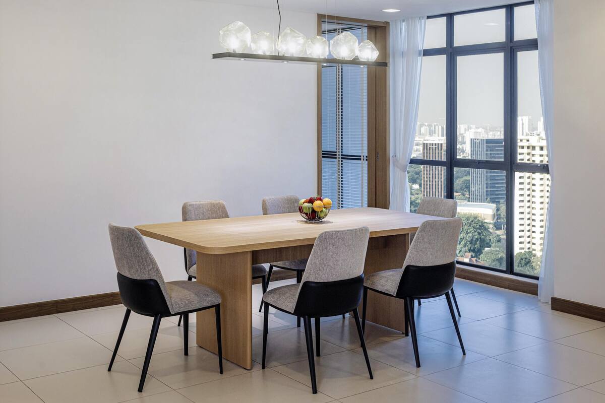 A modern dining area with a rectangular table, six chairs, a fruit bowl, and a unique pendant light.