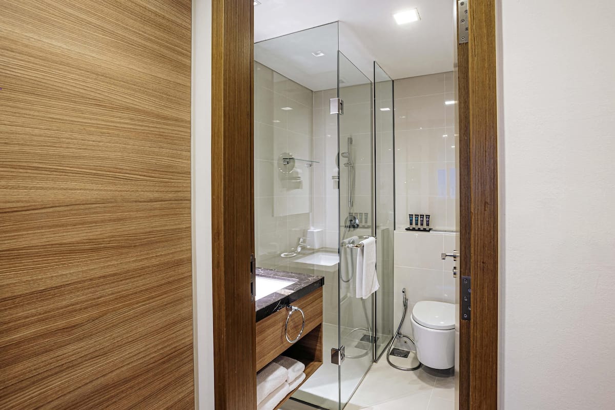 A modern bathroom with a glass shower enclosure, a wooden vanity, and a white toilet.