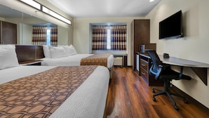Une chambre d’hôtel avec deux lits, un bureau, une chaise, une télévision et une fenêtre avec des rideaux.